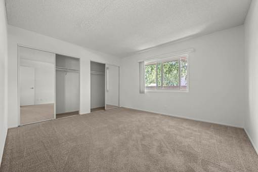 an empty living room with a window and a closet