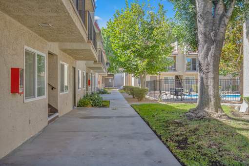 a sidewalk in front of a building with trees