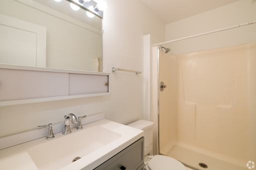 A white sink with two faucets and a toilet in a bathroom.