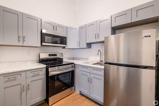 A kitchen with a stainless steel refrigerator, oven, and cabinets.