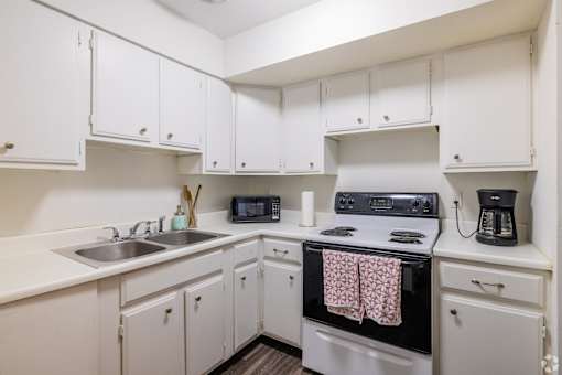 A white kitchen with a black stove top oven.