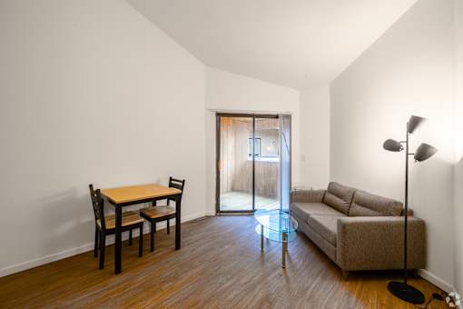 A living room with a brown couch, a wooden table and chairs, and a floor lamp.