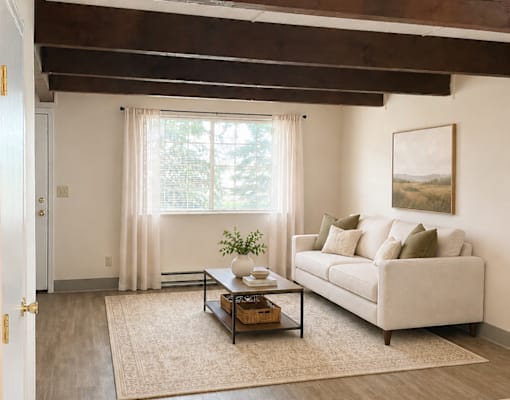 A living room with a couch, coffee table, and a painting on the wall.