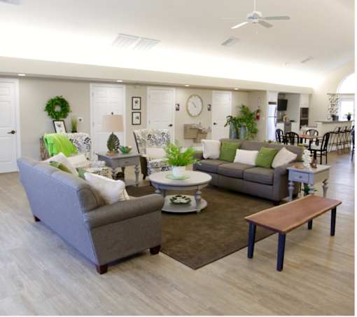 A living room with a grey couch, a green cushion, a white coffee table, and a brown bench.