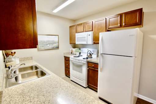 A kitchen with a white refrigerator, white oven, and white microwave.