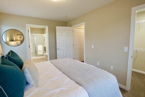 A bedroom with a large bed and a mirror on the wall.