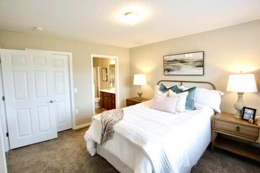 A bedroom with a large bed, a nightstand, and a door.