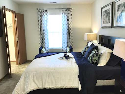 A bedroom with two beds and a nightstand with a lamp.