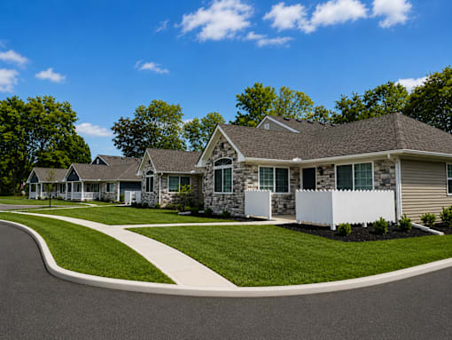 Apartment buildings with beige siding and porches with white fence.