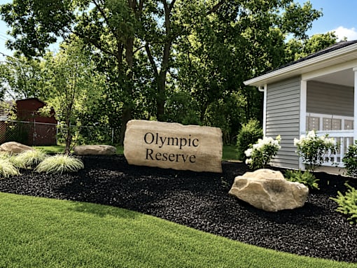 A large stone with the words Olympic Reserve to the left of a mailbox area.