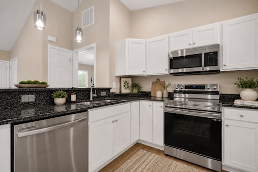 A kitchen with white cabinets and black countertops.