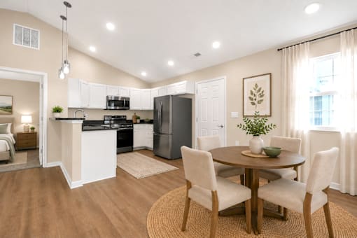 An open kitchen and dining area with white cabinets, black countertop and stainless steel appliances.