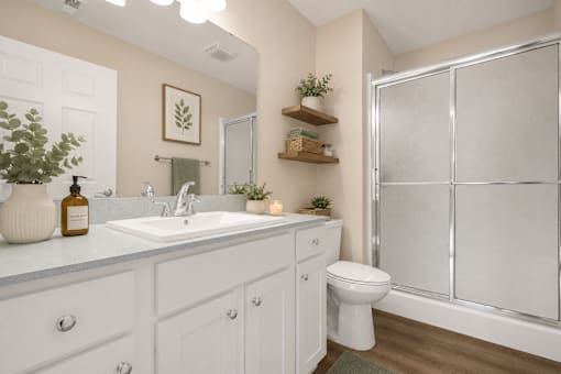 A white bathroom with a toilet, sink, and shower.