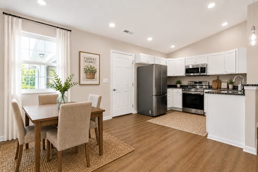 A kitchen with a dining table and chairs.