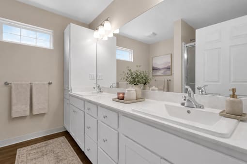 A bathroom with double sinks and white cabinets and countertops