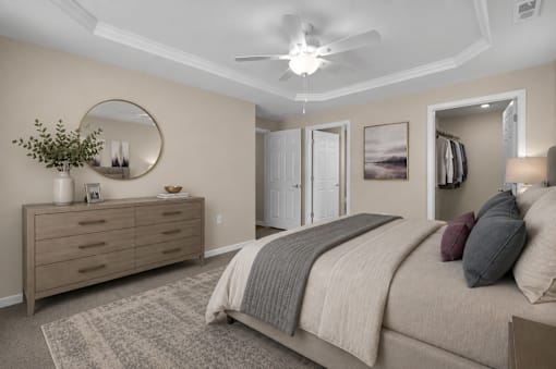 A bedroom with a bed, two nightstands and dresser in front of a closet and bathroom.