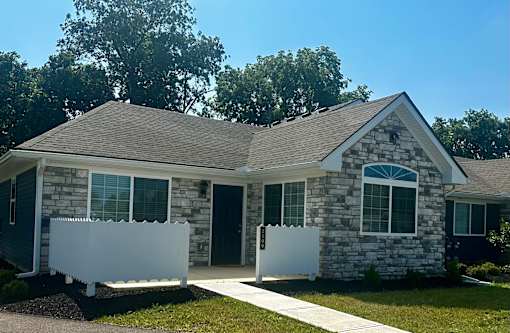 a stone house with two white fences in front of it