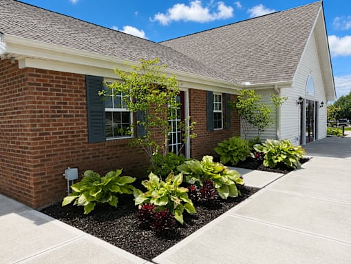 A small brick house with a white roof and a small garden in front.