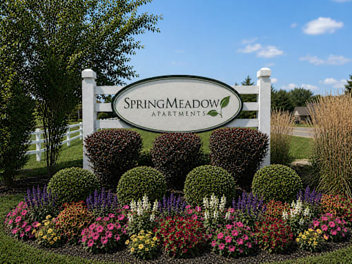 Spring Meadow Apartments sign with a garden in front.