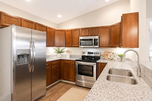 A kitchen with a refrigerator, microwave, oven, and sink.