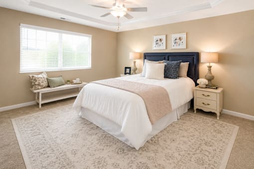 A bedroom with a large bed and a window with blinds.
