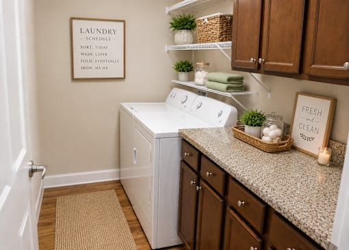A laundry sign hangs on a wall above a washer and dryer in a small laundry room.