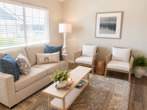 A living room with a beige couch, two chairs, a coffee table, and a rug.