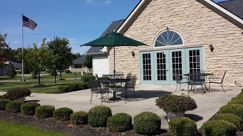 A house with a flag on the left and a patio with a table and chairs.