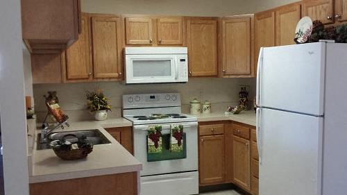 A kitchen with a white refrigerator, white oven, white microwave, and white sink.