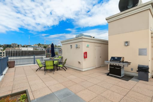 a rooftop patio with a grill and a table and chairs