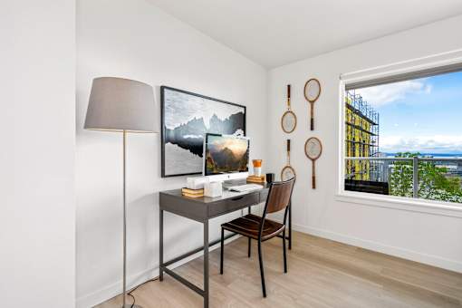 a desk with a chair and a lamp in a room with a large window