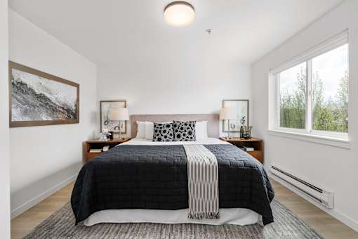 a bedroom with a large bed and two windows