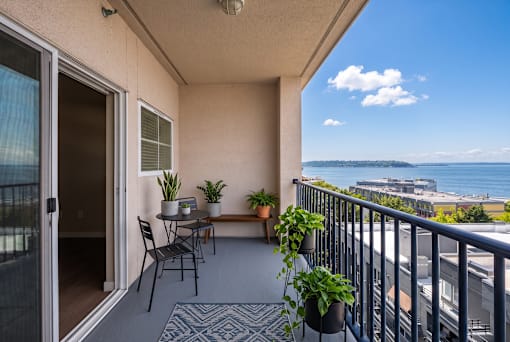 A balcony with a table and chairs overlooking the ocean.