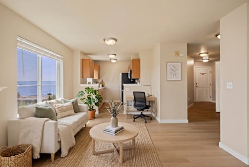 A living room with a couch, a coffee table, and a window overlooking the water.