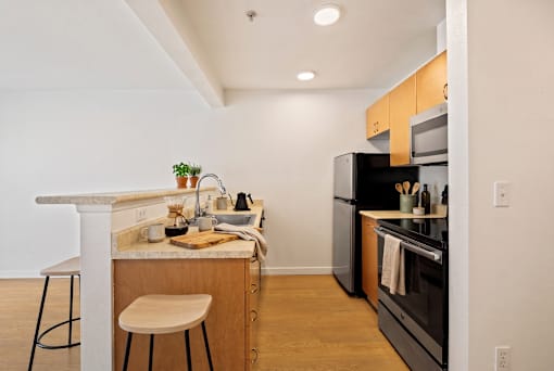 A kitchen with a white countertop and wooden stool.