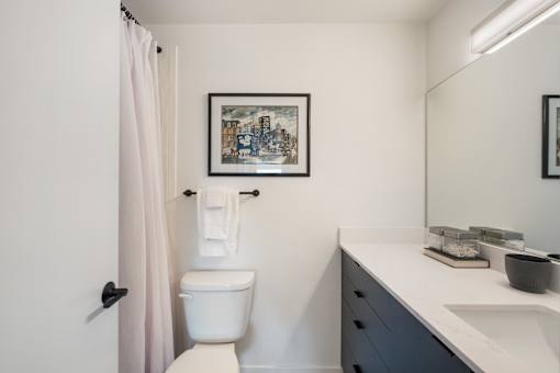 a bathroom with a white toilet next to a sink with a mirror above it