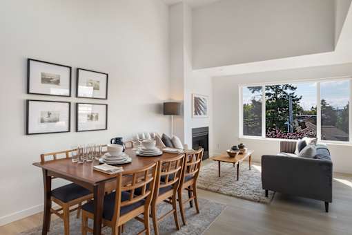 an open concept living room and dining room with a wooden table and chairs and a large window