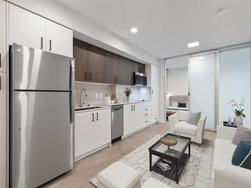 a white kitchen and living room with a stainless steel refrigerator