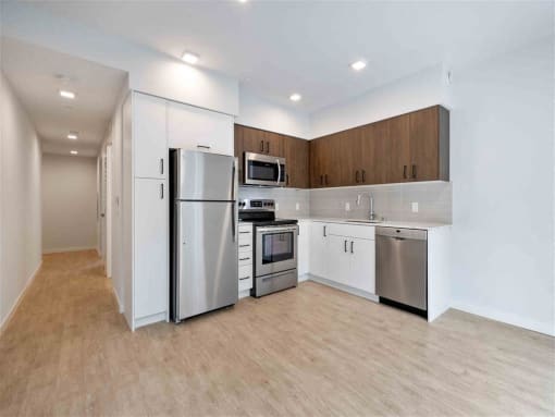 an empty kitchen with stainless steel appliances and white cabinets