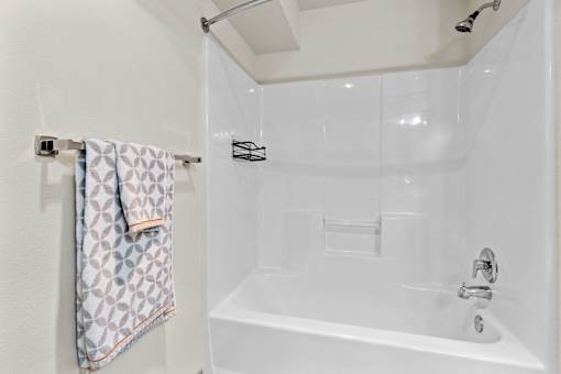 A white bathroom with a white tub and a towel hanging on the wall.