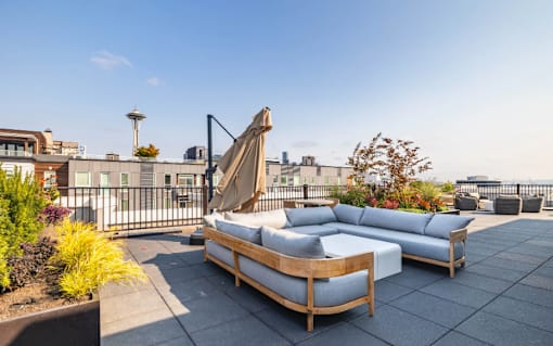 A patio with a couch and a table with a view of the city.