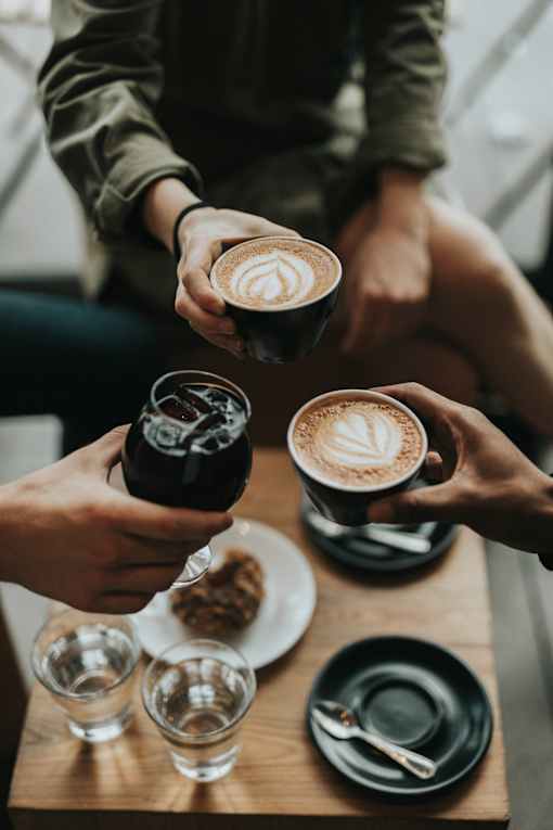 A person is holding a cup of coffee with a heart design on it.