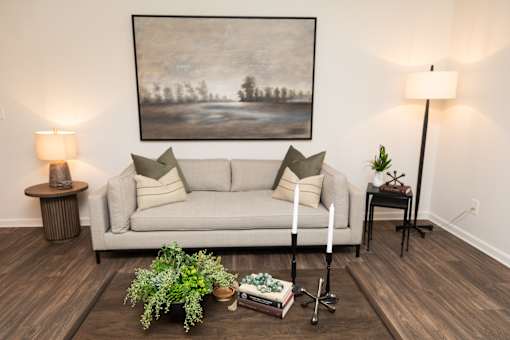 A living room with a grey couch, a painting on the wall, and a wooden floor. at Lakeside Villas, Hampton