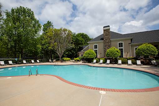 A large swimming pool surrounded by trees and lawn chairs. at Lakeside Villas, Hampton, Georgia
