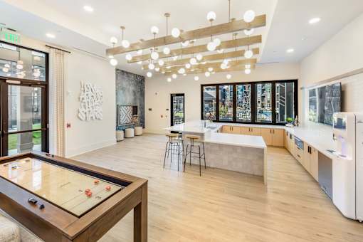 A room with a pool table and a kitchen area.