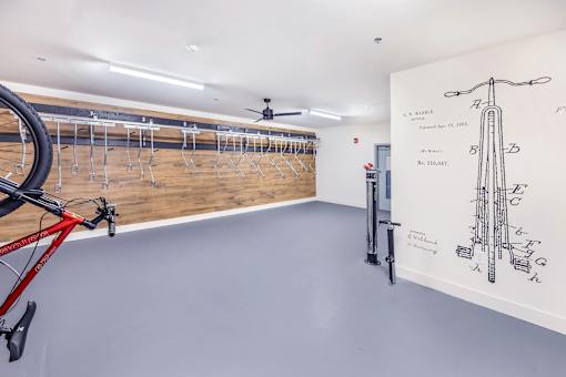 A bike is parked in a room with a wall drawing of a bike.