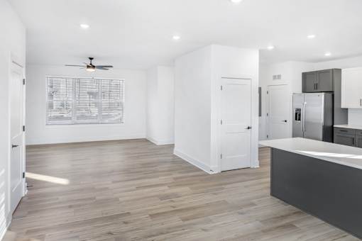 A spacious kitchen with a ceiling fan and wooden flooring.