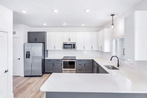 A modern kitchen with a white countertop and stainless steel appliances.