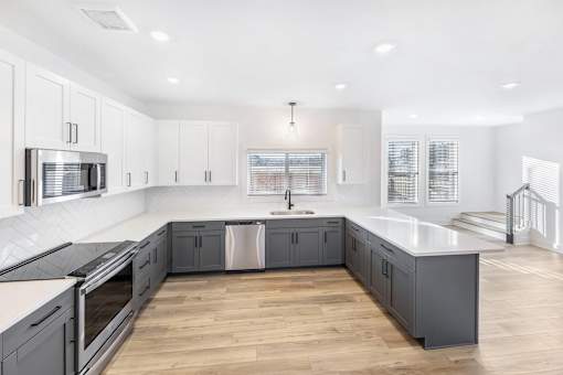 A modern kitchen with wooden floors and white cabinetry.