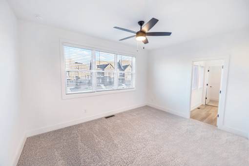 A room with a ceiling fan and a window with blinds.